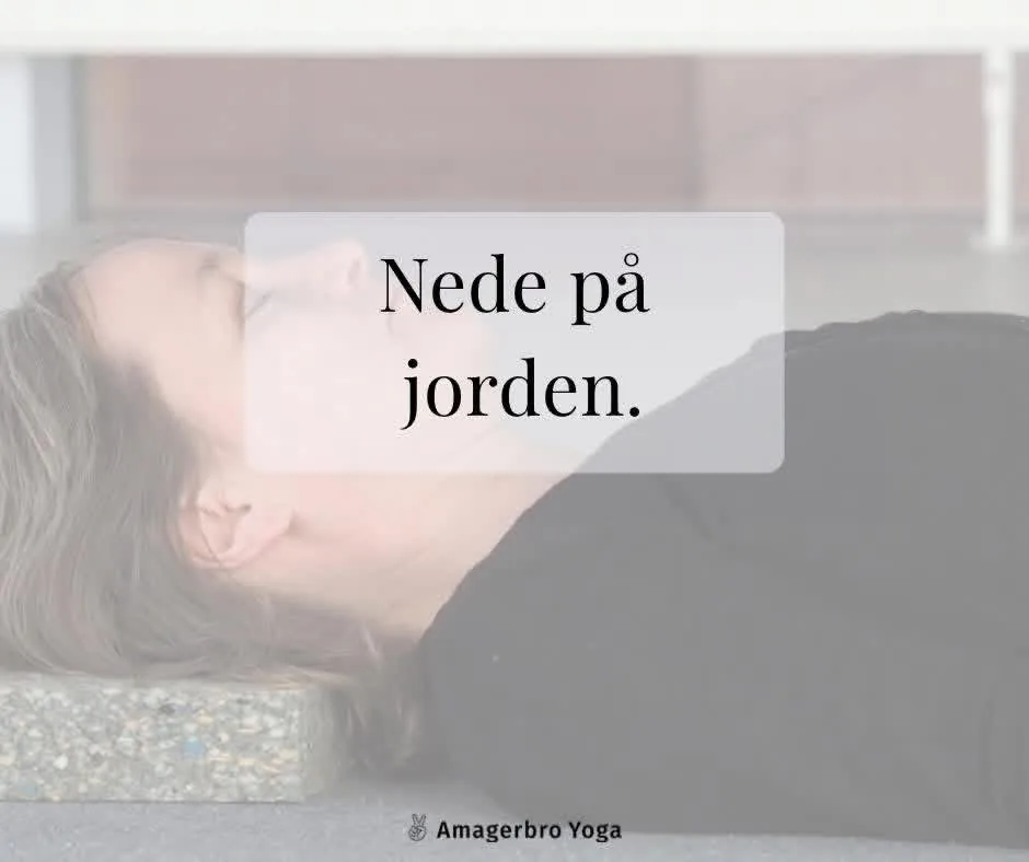 Kvinde ligger afslappet på ryggen på gulvet med hovedet hvilende på en yogaklods
