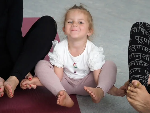 Glad barn sidder med krydsede ben til børneyoga