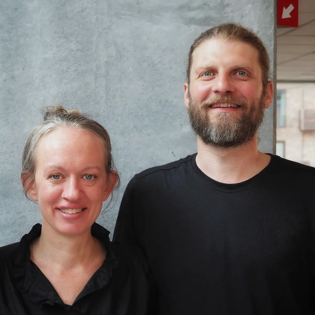 Cathrine og Jonas, underviserne bag Amagerbro Yoga, foran en betonvæg