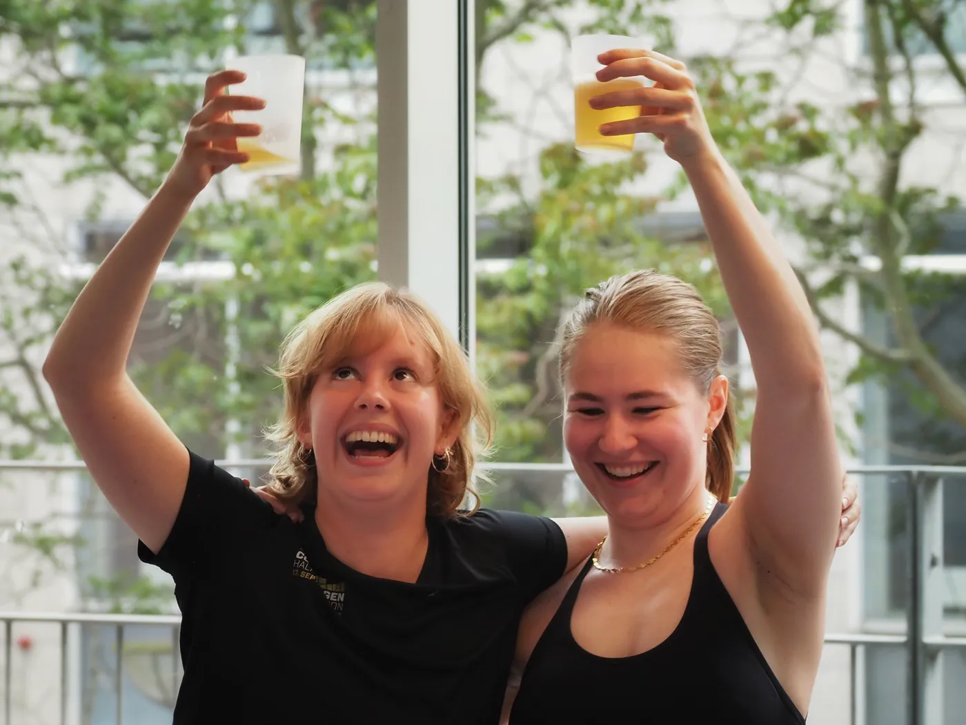 To veninder skåler med armene om hinanden til drinksyoga