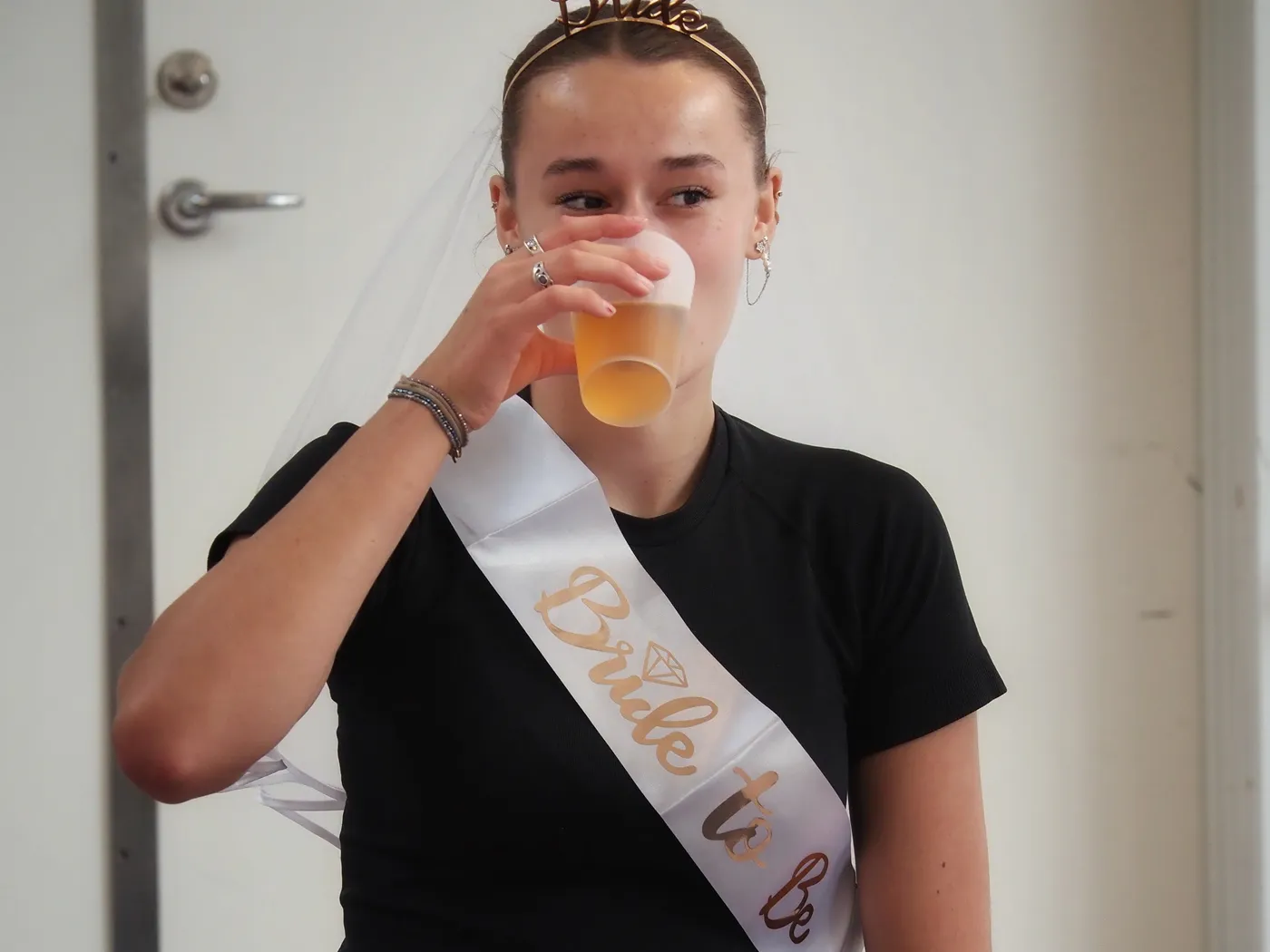 Bruden med Bride to be-bånd og slør tager en tår af sin drink
