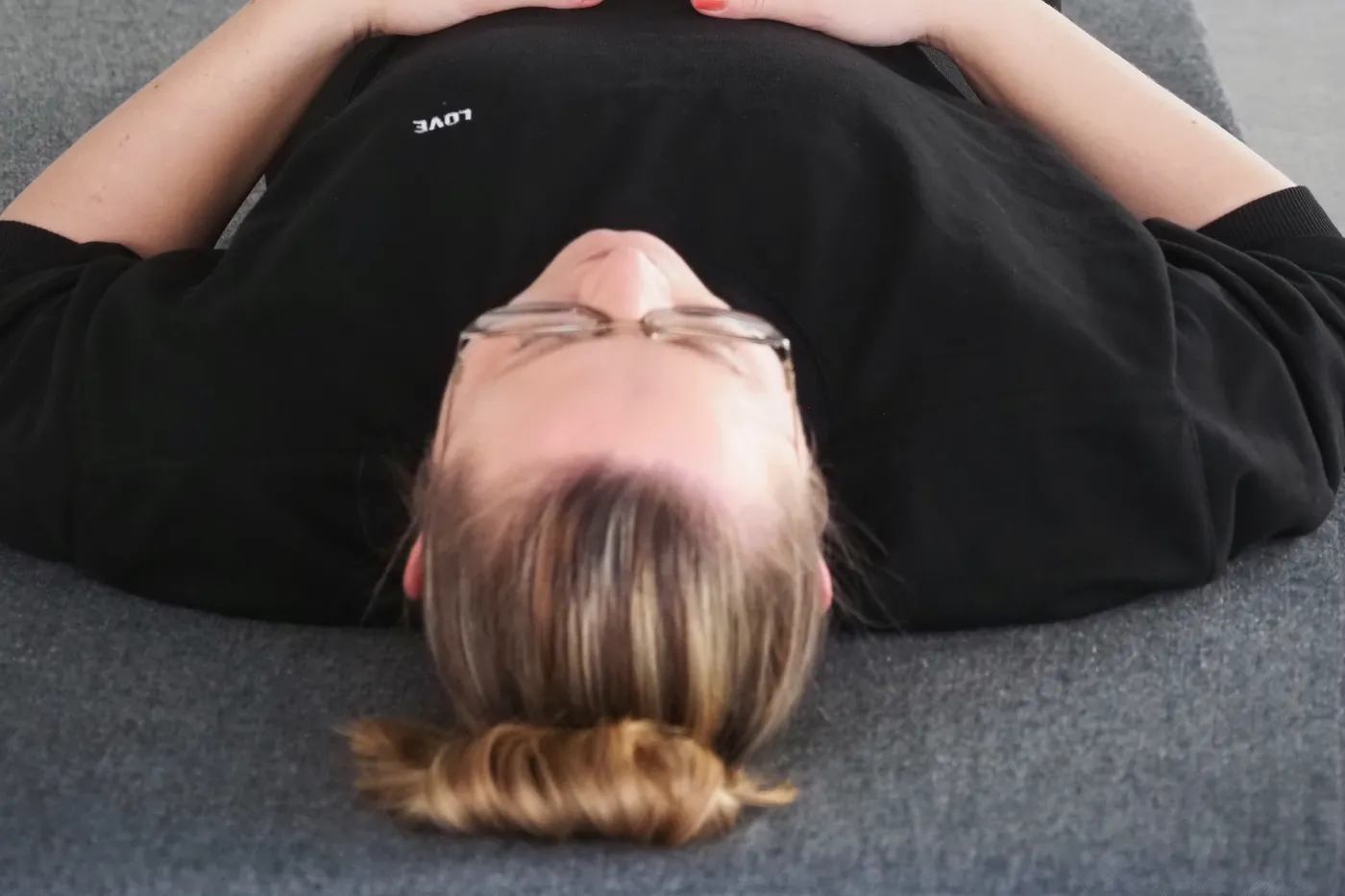 Deltager hviler på ryggen med hænderne på maven til yin yoga
